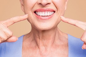 a denture patient pointing to her smile