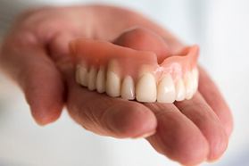 a hand holding a denture