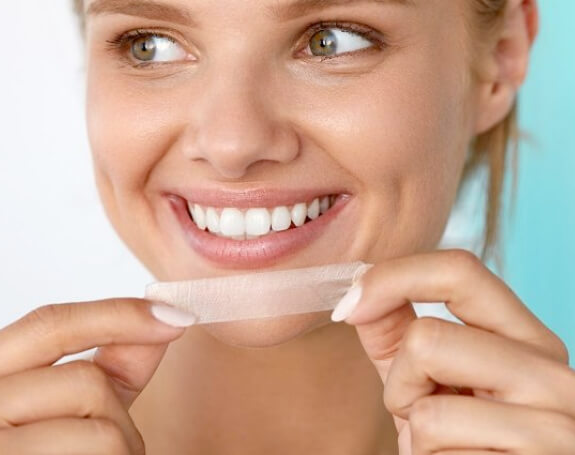 Woman using teeth whitening strips