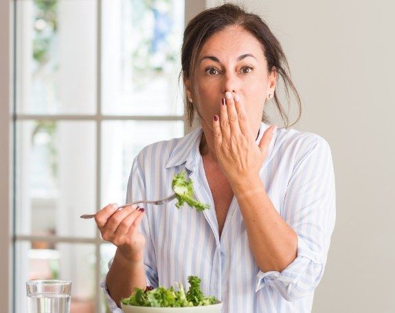 Woman in need of emergency dentistry covering her mouth