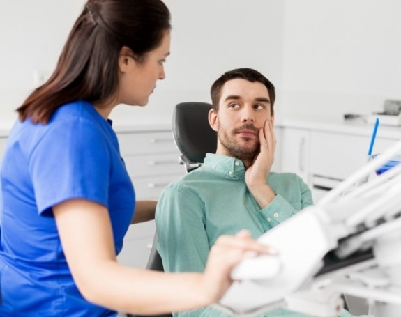 Man in need of emergency dentistry holding cheek in pain