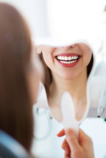 Woman looking at her beautiful smile in the mirror