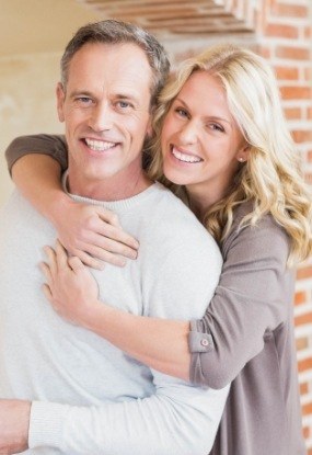 Man and woman smiling after tooth replacement with dental implants