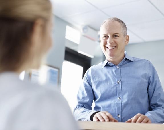 Man discussing the cost of dental implants with dental team member