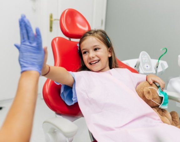 Young girl giving dentist a high five during children's dentistry visit