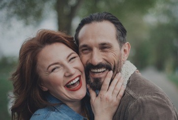 Man and woman smiling after dental implant tooth replacement