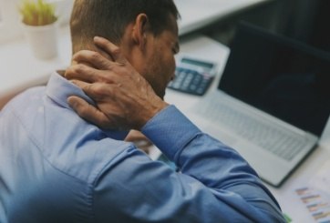 Man in need of T M J therapy holding neck in pain