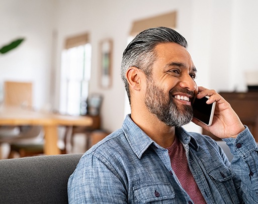 Man smiling while talking on phone at home