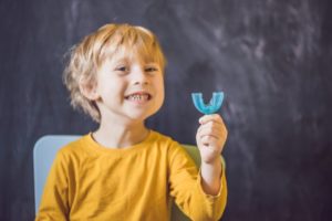 Smiling boy holds custom mouthguard from his Painesville dentist