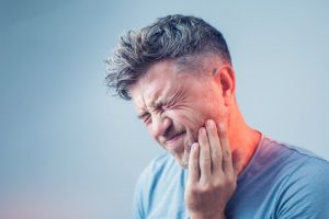 a man holding his cheek due to a toothache