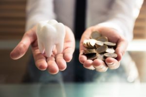 Painesville dentist holding model tooth and pile of coins