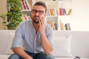 man with a toothache holding his cheek in pain 