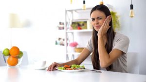 woman eating salad with a toothache 