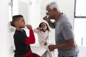 Older man and two small children brushing their teeth