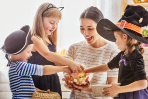 Kids in costume reaching into Halloween candy bowl